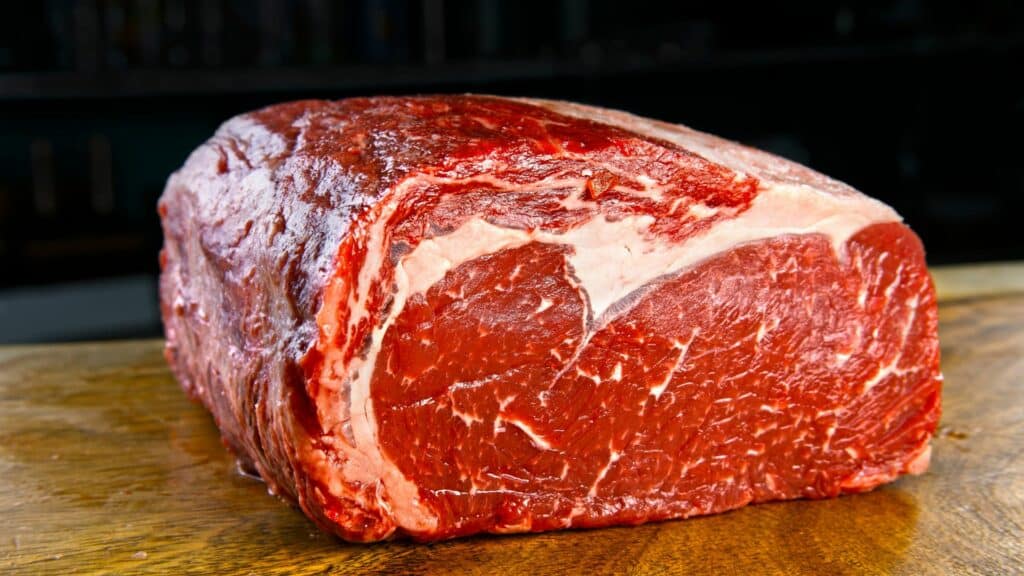 Imagem de um pedaço de angus crú - carne de boi - sobre uma mesa de madeira.