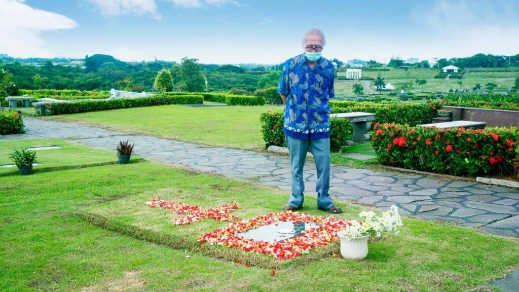 Imagem de um homem visitando o túmulo em um cemitério.