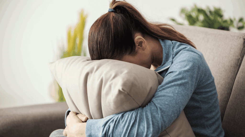 Uma mulher que está triste e cabisbaixa está abraçando uma almofada.
