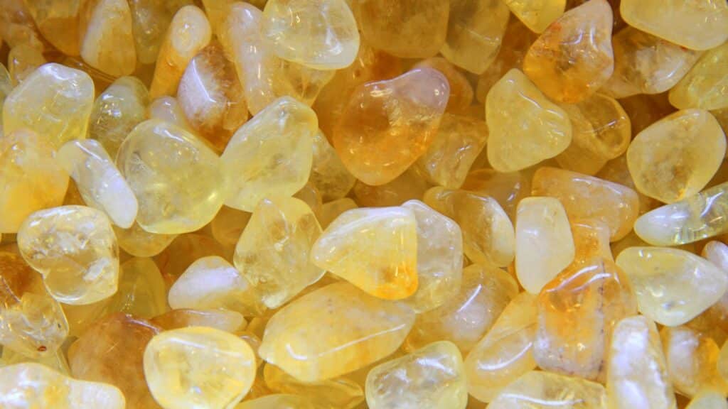 Imagem de várias pedrinhas e cristais de quartzo amarelo, separados para uso em um ritual mágico.