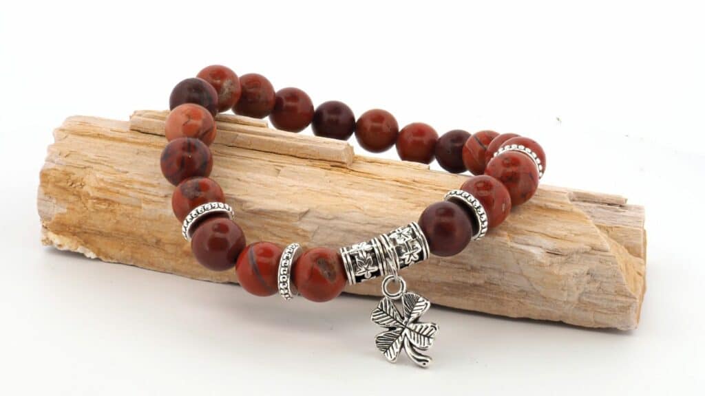 Imagem de uma linda pulseira feita com as pedras de jaspe marrom. Ela está sobre um pedaço de tronco para se destacar ainda mais.