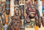 Na imagem, há várias máscaras feitas por um povo africano que estão penduradas na parede.