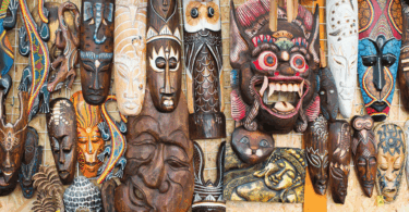 Na imagem, há várias máscaras feitas por um povo africano que estão penduradas na parede.