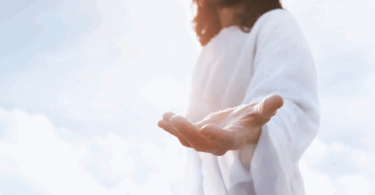 Na imagem, Jesus está estendendo uma de suas mãos para frente. Ao fundo, há nuvens e luz.