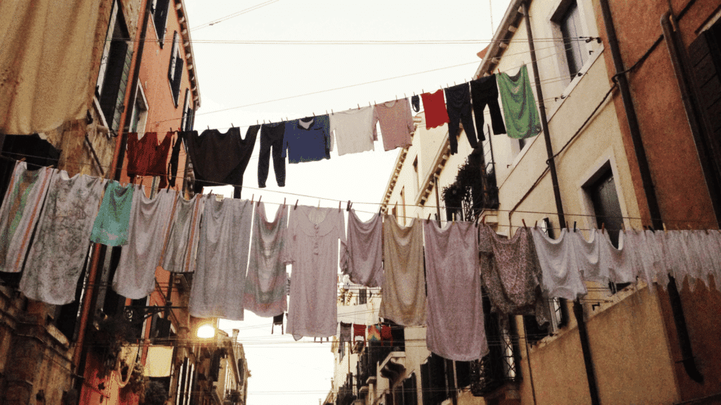 Há vários prédios e roupas no varal penduradas de um prédio para o outro.