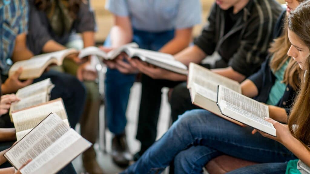 Grupo de estudantes lendo seus livros em um espaço de sala de aula, uma forma de exercer a cidadania tendo acesso à educação.
