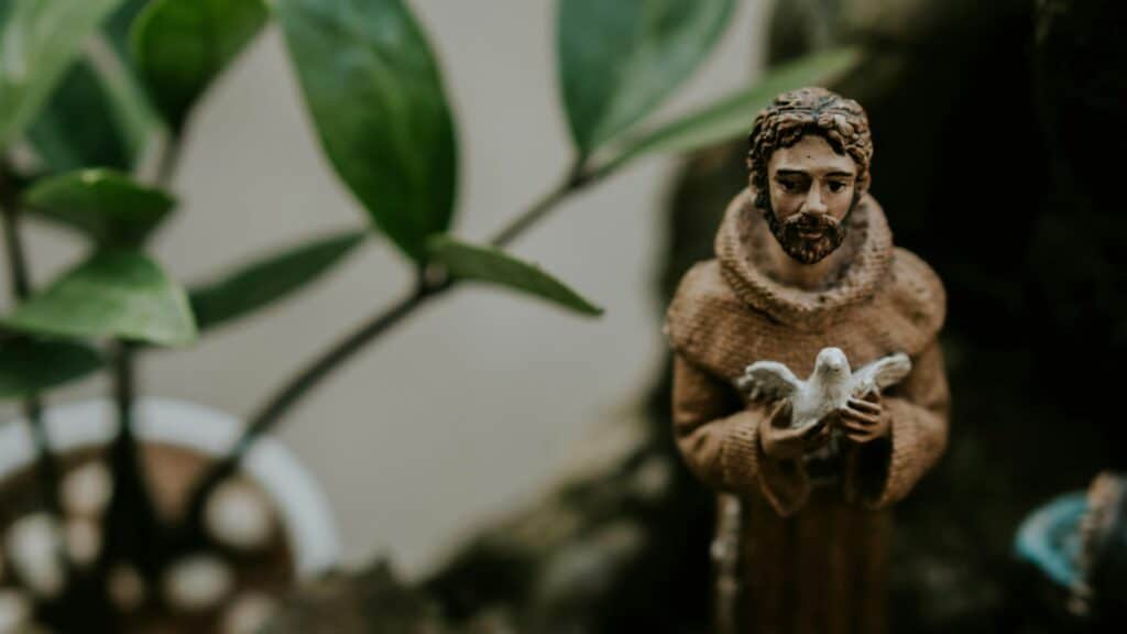 Imagem de uma pequena estátua de São Francisco de Assis, segurando uma pomba branca.

