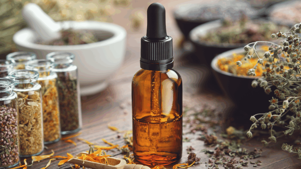 No foco da imagem, há um frasco com óleo essencial. Ao redor, há algumas plantas ou flores trituradas e armazenadas em outros frascos.
