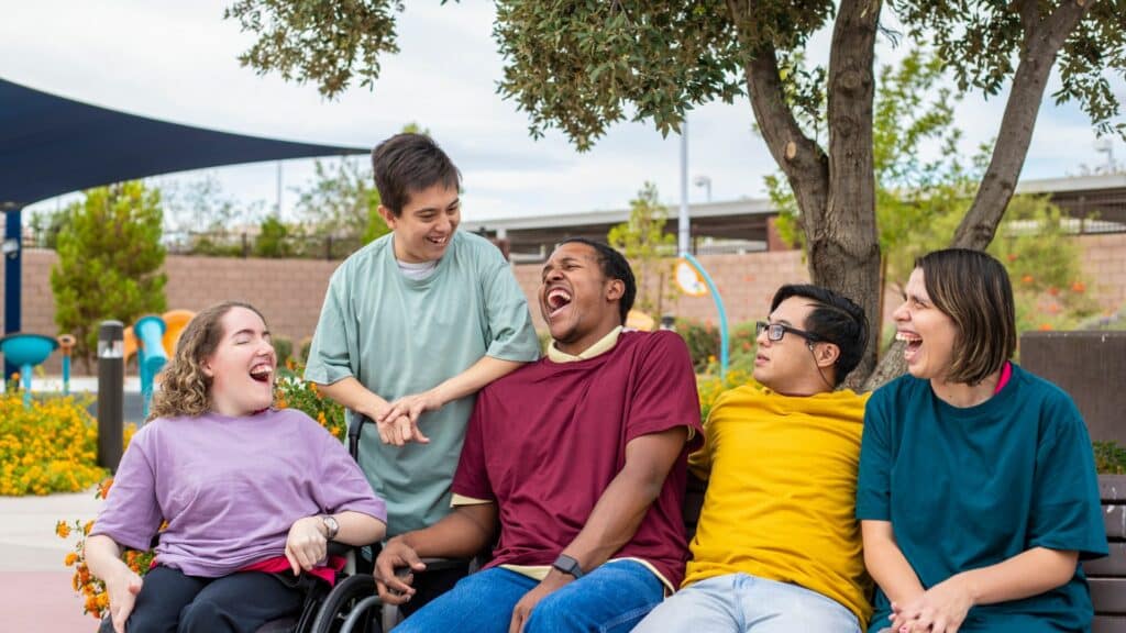 Imagem de várias pessoas sentadas, cada uma com uma necessidade especial, filhos de mães atípicas dentro de uma organização social que os ajudam no dia a dia.