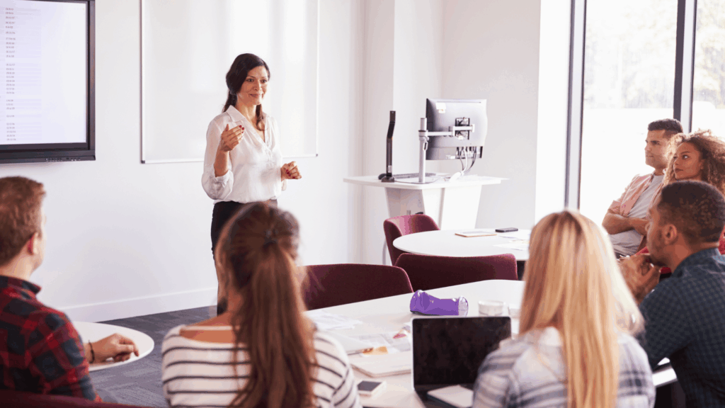 Uma mulher de negócios apresenta uma palestra ou uma aula em uma universidade. Ela está em uma sala de aula apresentando para alunos universitários.