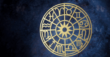 Uma roda do zodíaco está em destaque na imagem. Há um fundo azul escuro.