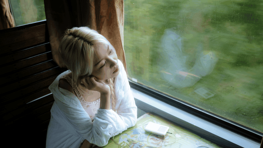 Mulher jovem está contemplativa e olhando através da janela do trem.