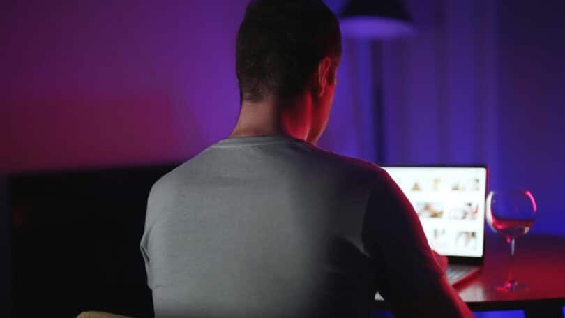 Imagem de um homem assistindo secretamente a sites pornográficos à noite.