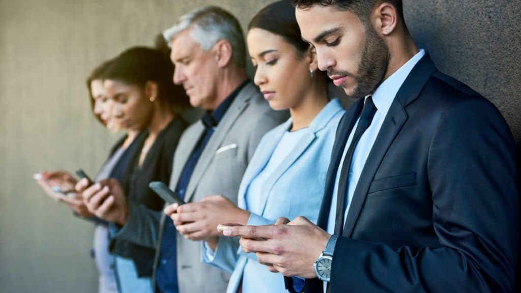 Imagem de várias pessoas, de várias idades, com os seus celulares em mãos acessando às redes e usando as novas tecnologias, simbolizando o acesso a todas informações.