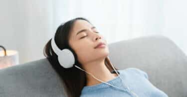 Imagem de uma mulher sentada em seu sofá, ouvindo músicas e revivendo memórias por meio das músicas que ela ouve.