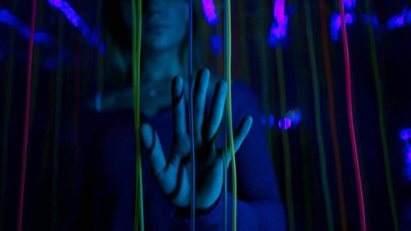 Imagem da mão de pessoa com luzes azuis e roxas, simbolizando o Transtorno da Sobrecarga Sensorial - TSS