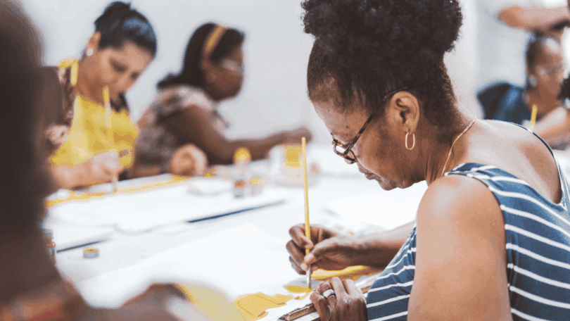 Um grupo de mulheres está pintando telas.
