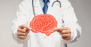 Médico segurando ilustração de um cérebro, simbolizando cuidado e saúde mental.