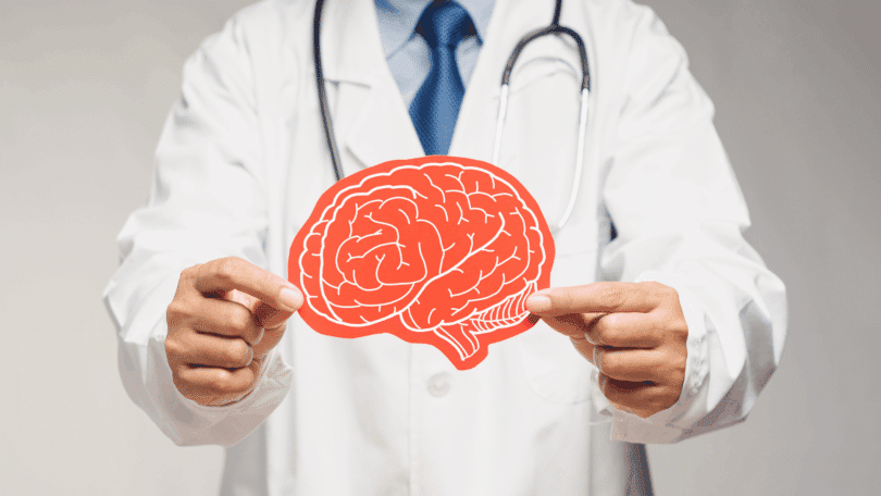 Médico segurando ilustração de um cérebro, simbolizando cuidado e saúde mental.