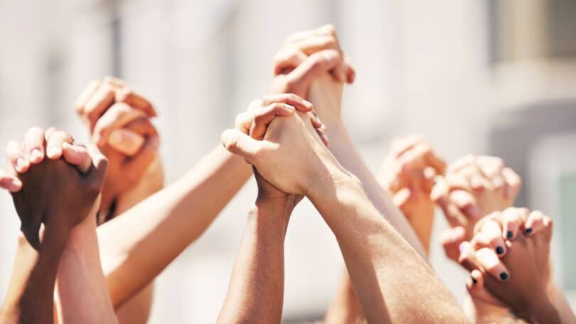 Imagem de vários mãos dadas ao alto, simbolizando a união e a justiça social.