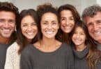 Imagem de várias pessoas, homens, mulheres e uma criança, unidos, sorrindo, trazendo o conceito de pertencimento, comunidade e união.