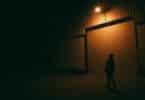 Imagem com a silhueta de homem na rua, sobre uma luz amarela. A foto traz o conceito das pessoas que vivem presas na superfície da ramificação atual, acreditando que esta é a única realidade. Elas sofrem pelo passado e temem o futuro.