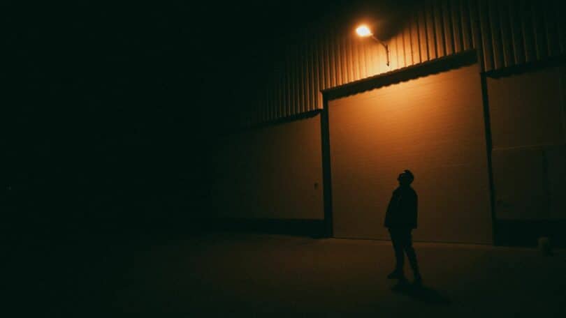 Imagem com a silhueta de homem na rua, sobre uma luz amarela. A foto traz o conceito das pessoas que vivem presas na superfície da ramificação atual, acreditando que esta é a única realidade. Elas sofrem pelo passado e temem o futuro.