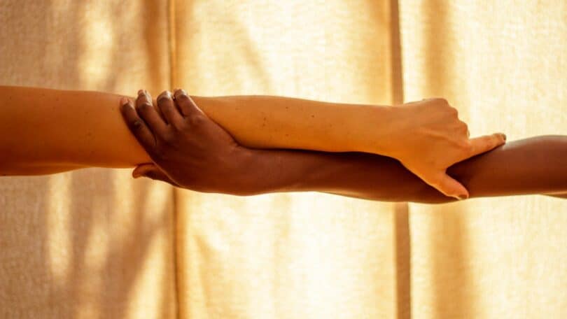 Imagem de uma luz quente que banha duas mãos entrelaçadas, simbolizando a freqüência, a conexão e a relação entre as pessoas.