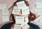 Mulher deitada com post-its cobrindo o rosto, com palavras relacionadas a pressão e produtividade.