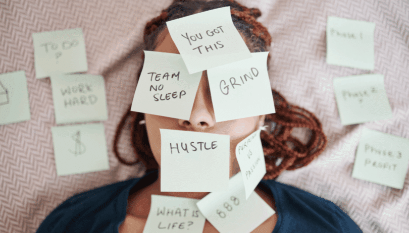 Mulher deitada com post-its cobrindo o rosto, com palavras relacionadas a pressão e produtividade.