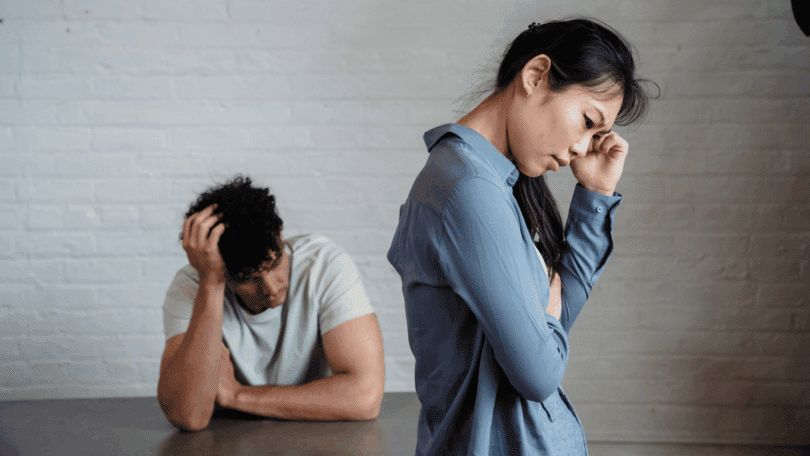 Um casal composto por um homem e uma mulher demonstram tensão e tristeza em um momento de conflito ou distanciamento emocional.