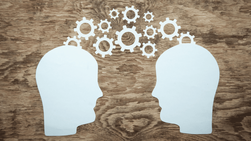 Silhuetas de duas cabeças conectadas por engrenagens simbolizam troca de ideias, comunicação e funcionamento da mente.