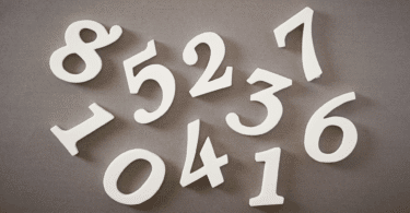 Números brancos espalhados sobre uma superfície neutra, representando contagem, cálculos ou conceitos matemáticos.