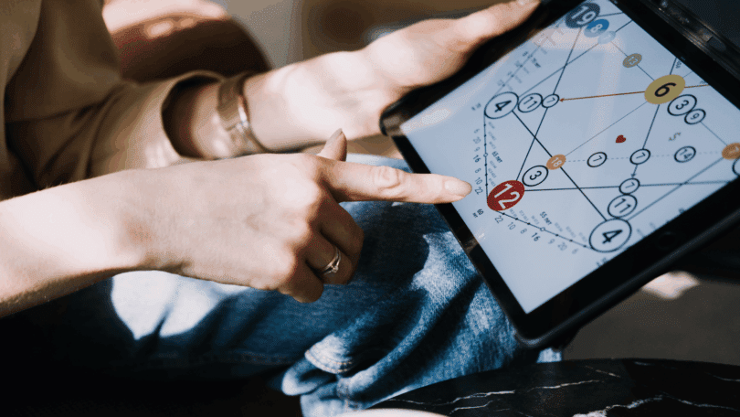 Mulher aponta para um gráfico numerológico em tablet, explorando padrões e interpretações ligadas ao autoconhecimento e ao desenvolvimento pessoal.