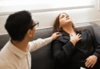Mulher aparenta estar em crise de ansiedade ou mal-estar emocional enquanto recebe apoio de outra pessoa sentada ao seu lado.