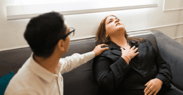 Mulher aparenta estar em crise de ansiedade ou mal-estar emocional enquanto recebe apoio de outra pessoa sentada ao seu lado.