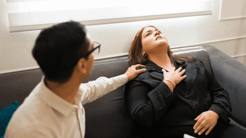 Mulher aparenta estar em crise de ansiedade ou mal-estar emocional enquanto recebe apoio de outra pessoa sentada ao seu lado.