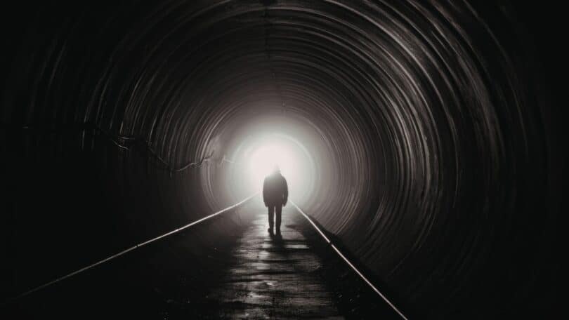 Imagem de um caminho em formato de espiral com uma pessoa caminhando em direção ao centro ou à saída, representando a repetição de padrões e a possibilidade de transformação emocional.