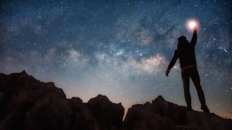 Imagem de uma silhueta humana cercada por um céu estrelado, criando uma atmosfera de mistério, introspecção e questionamento sobre a natureza da consciência e do observador interior.