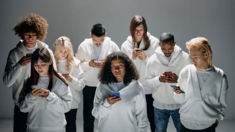 Imagem de várias pessoas segurando seus celulares trazendo o conceito de hiperconexão e isolamento.