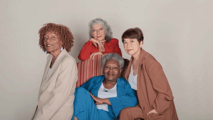 Quatro mulheres idosas posam juntas para um retrato, representando diversidade, elegância e união.