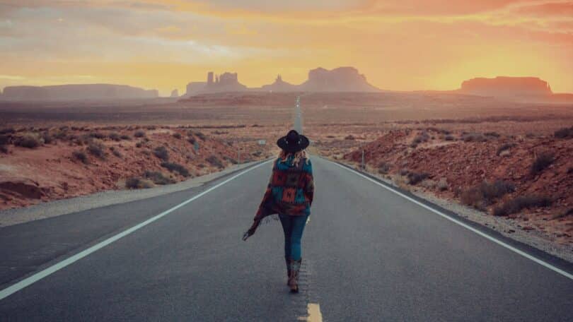 Imagem de uma pessoa caminhando sozinha por uma estrada ao nascer do sol, envolta por uma luz dourada, transmitindo introspecção, esperança e recomeço.