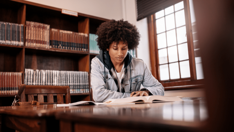 Imagem de uma pessoa estudando sozinha em um ambiente silencioso e acolhedor, com livros sobre a mesa.