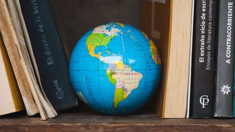 Imagem de vários livros de filosofia em uma estante e ao centro, o globo terrestre.